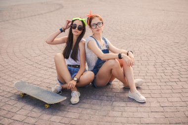 Two beautiful young girls on a skateboard in the city.