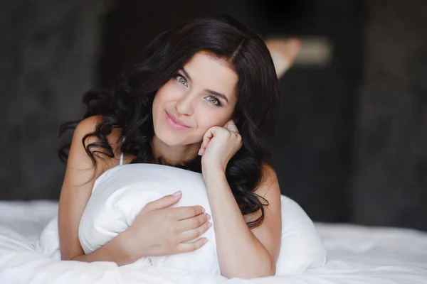 Young woman hugging a white cushion — Stockfoto