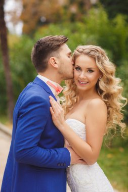 Damat gelini yeşil bir parkta yaz aylarında kisses.