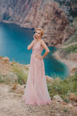 Gelin gelinlik üst güzel deniz manzaralı bir uçurumun üzerinde duruyor