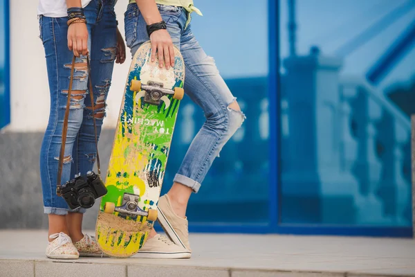 Duas belas e jovens namoradas se divertindo com um skate — Fotografia de Stock