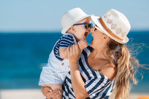 Una giovane madre e il suo delizioso figlioletto in vacanza sulla spiaggia Immagine Stock