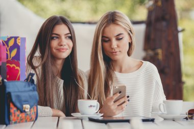 Two girls in a cafe listening to music in earphone