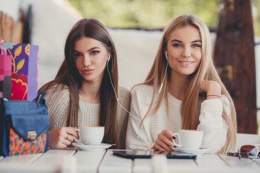 Two girls in a cafe listening to music in earphone