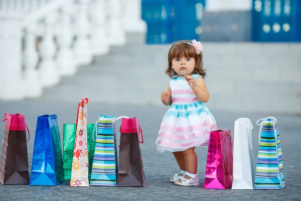 Little girl and lots of colorful bags — Zdjęcie stockowe