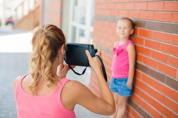 Mom photographs her daughter on the street in the city in the summer — Stockfoto
