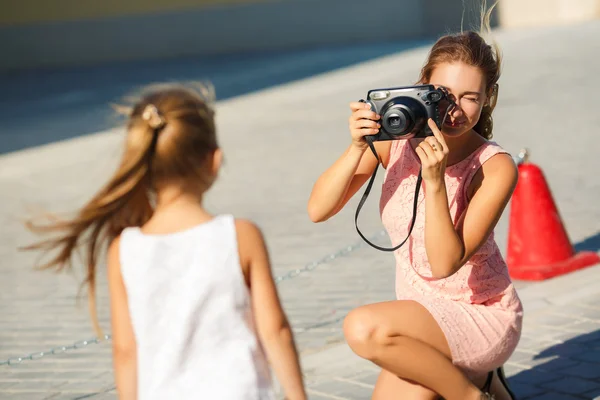 Mom photographs her daughter on the street in the city in the summer — Stock Photo, Image