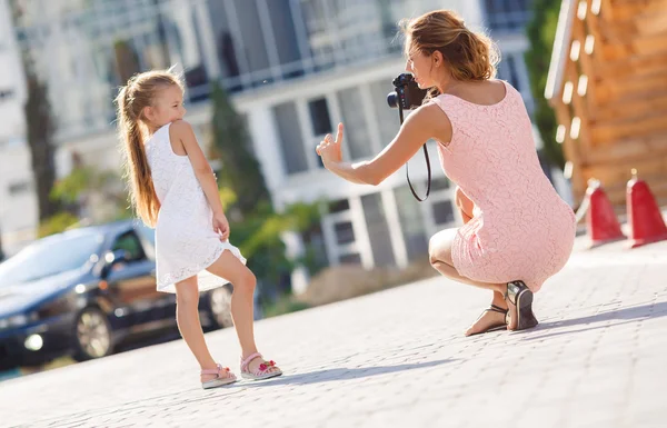 Mom photographs her daughter on the street in the city in the summer — Zdjęcie stockowe