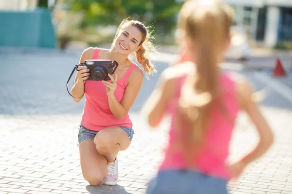 Mom photographs her daughter on the street in the city in the summer — Zdjęcie stockowe