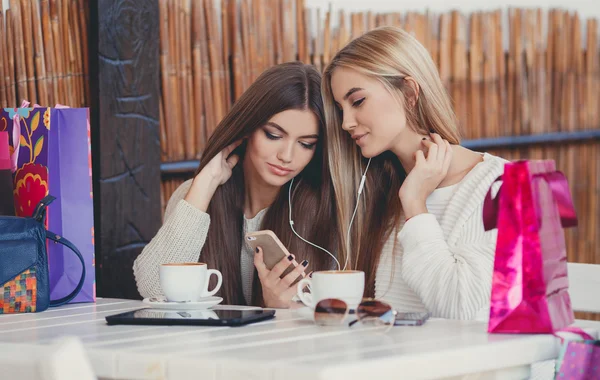 Two girls in a cafe listening to music in earphone — 图库照片