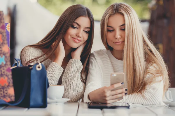 Two young women at cafe looking at pictures of new gadgets — Stock Photo, Image