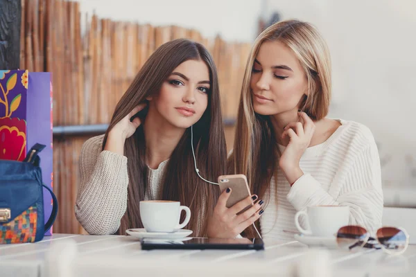 Two girls in a cafe listening to music in earphone