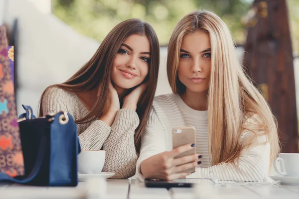 Two young women at cafe looking at pictures of new gadgets — Stok fotoğraf
