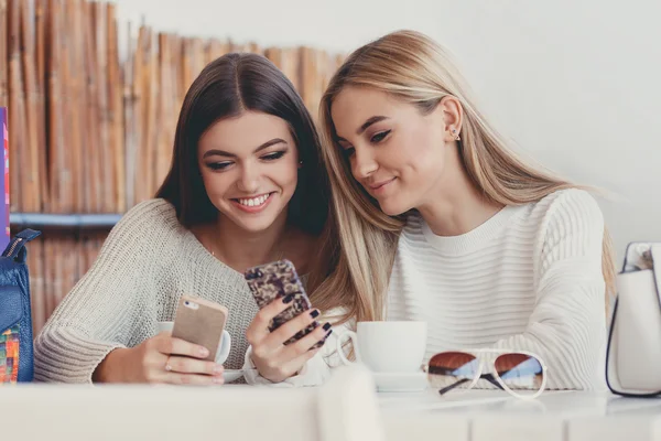 Two young women at cafe looking at pictures of new gadgets — Zdjęcie stockowe