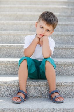 The boy sitting on the stairs in the underpass