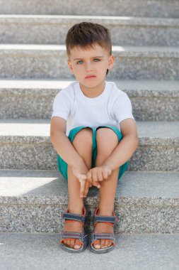The boy sitting on the stairs in the underpass