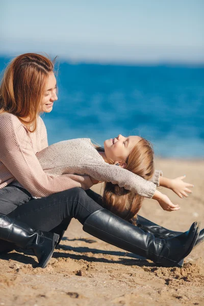 Happy mother and daughter playing on the nature of the sea — Stock Photo, Image