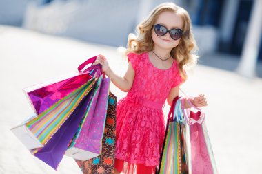 Little girl with shopping bags goes to the store