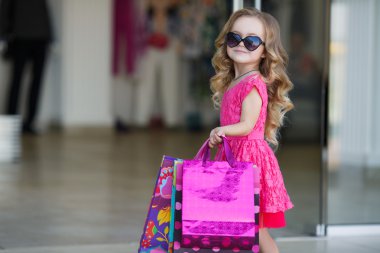 Little girl with shopping bags goes to the store