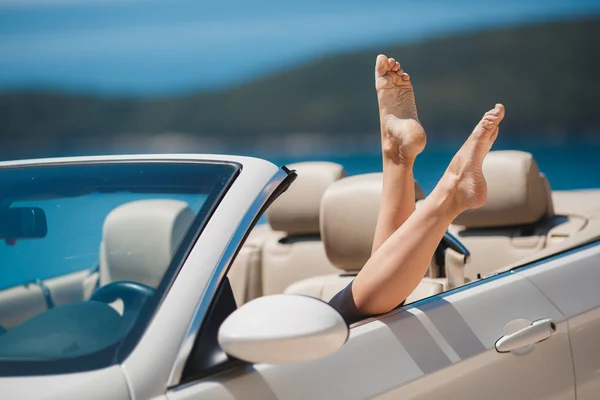 Schlanke Frauenbeine schauen aus dem Autofenster. — Stockfoto