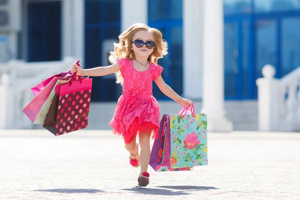 Little girl with shopping bags goes to the store — 스톡 사진