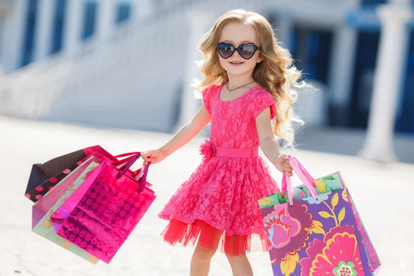 Little girl with shopping bags goes to the store — Stok fotoğraf