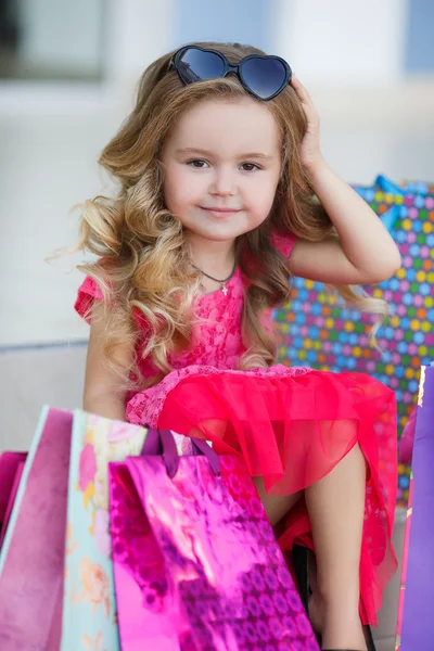Kleines Mädchen mit Einkaufstüten geht in den Laden — Stockfoto