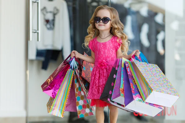 Little girl with shopping bags goes to the store — Stock Photo, Image