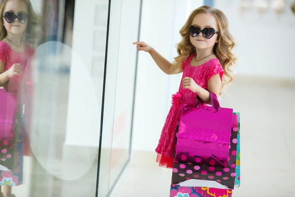Little girl with shopping bags goes to the store — 图库照片
