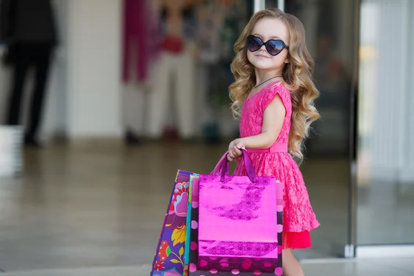 Petite fille avec des sacs à provisions va au magasin — Photo