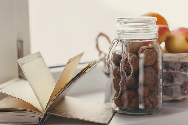 Autumn still life with nuts and citrus on a white windowsill. — Stock Photo, Image