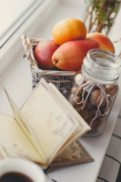 Autumn still life with nuts and citrus on a white windowsill. — Stock Photo, Image