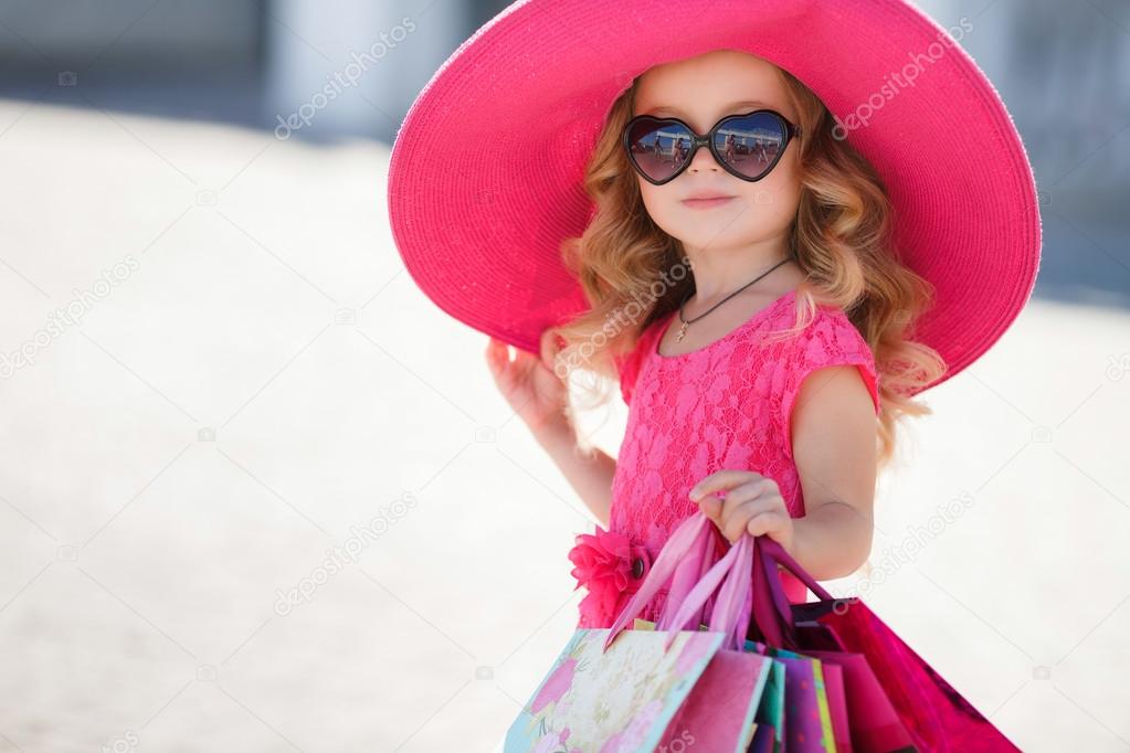 Fashionable little girl in a hat with shopping bags
