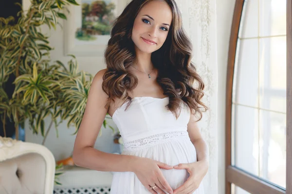 Portret van zwangere vrouw staan in de kamer in de buurt van het venster — Stockfoto