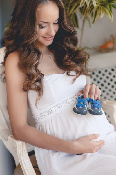 Mulher grávida barriga segurando botas de bebê . — Fotografia de Stock