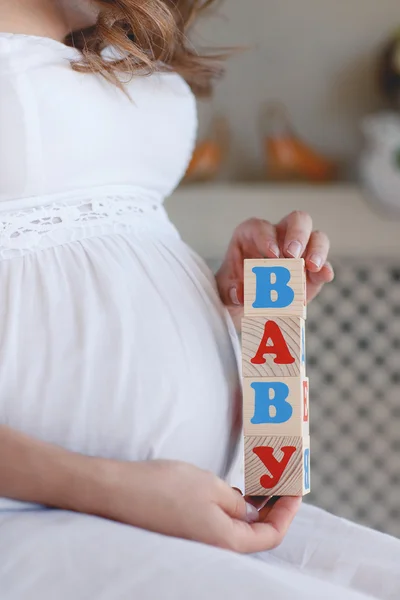 La femme enceinte avec des cubes de jouets dans les mains . — Photo