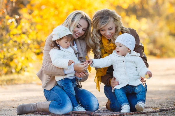 Moms and kids for a walk in the park in autumn — Stockfoto