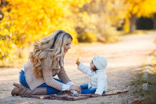 Mom and daughter resting in a park in autumn — 图库照片