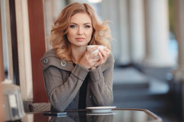 Bir kafede kahve içen bir kadın.