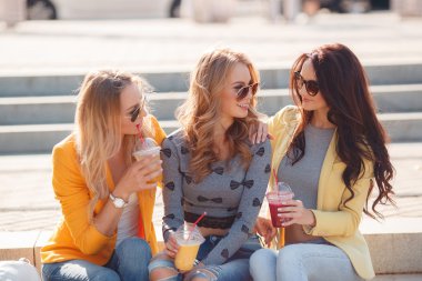 Three smiling women sitting on the steps in the Park