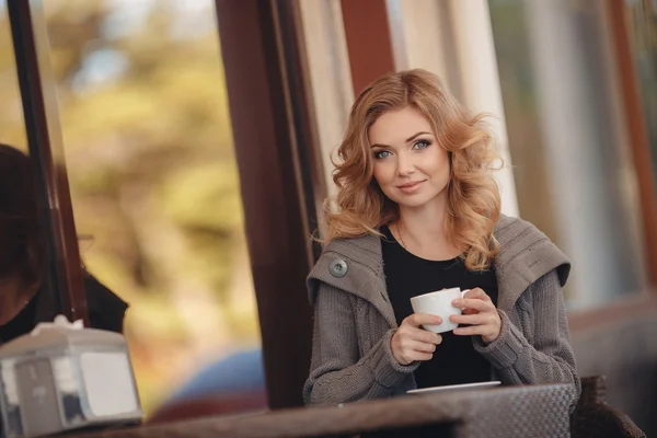 Женщина пьет кофе за столом в кафе — стоковое фото