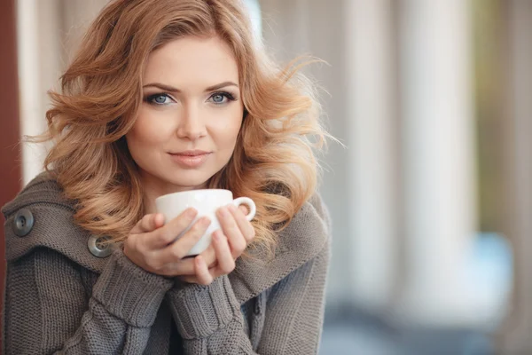 Mulher bebendo café em uma mesa em um café — Fotografia de Stock