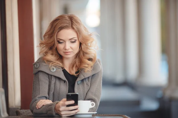 Mujer tomando café en una mesa en un café —  Fotos de Stock