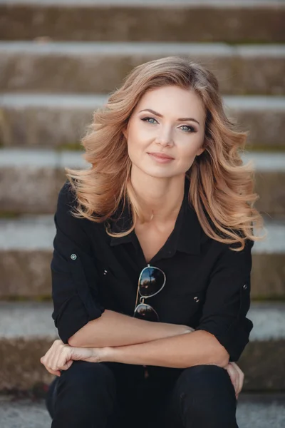 Portrait of a beautiful blonde in the Park on the stairs — Stockfoto
