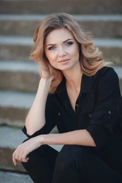 Porträt einer schönen Blondine im Park auf der Treppe — Stockfoto