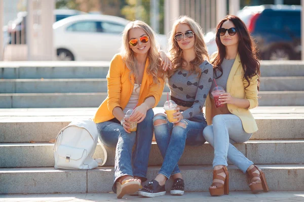 Three smiling women sitting on the steps in the Park — Stok fotoğraf