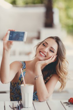 Genç kadın ile akıllı telefon kendi kendine portre (selfie) bir Paris sokağı kafede alarak