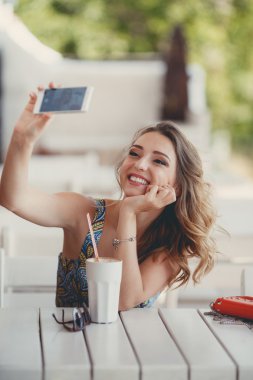 Genç kadın ile akıllı telefon kendi kendine portre (selfie) bir Paris sokağı kafede alarak