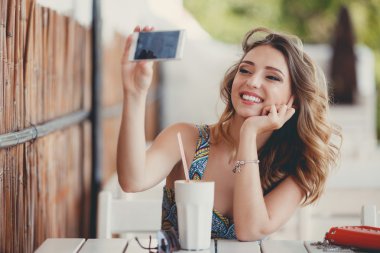 Genç kadın ile akıllı telefon kendi kendine portre (selfie) bir Paris sokağı kafede alarak