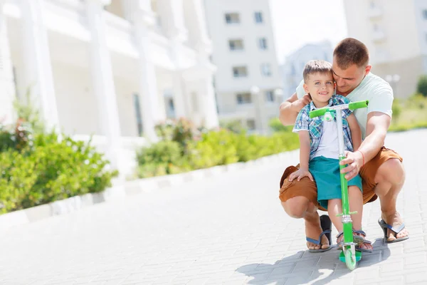 Pai ensinando filho a andar de scooter — Fotografia de Stock